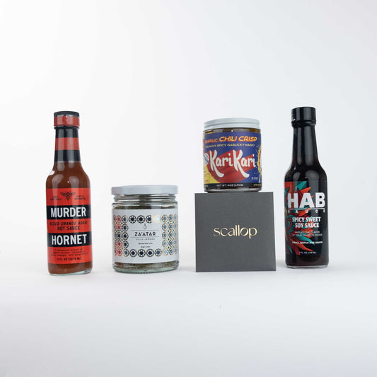 Scallop Heat Wave hot sauce collection featuring Garlic Chili Crisp, Blood Orange Agave hot sauce, Hornet, Murder, KariKari, Soy Sauce, and Za'atar arranged in a flat lay product shot.