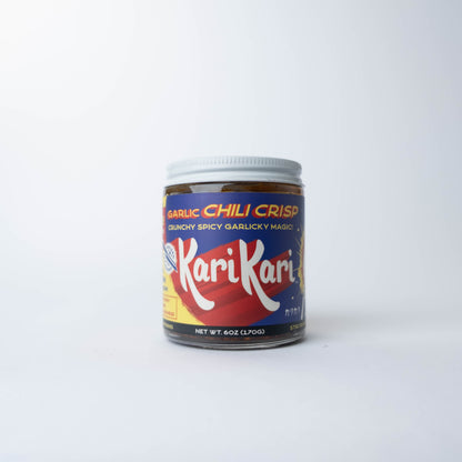 KariKari Garlic Chili Crisp in a clear glass jar with a white lid and colorful blue, red, and yellow label on a white background.