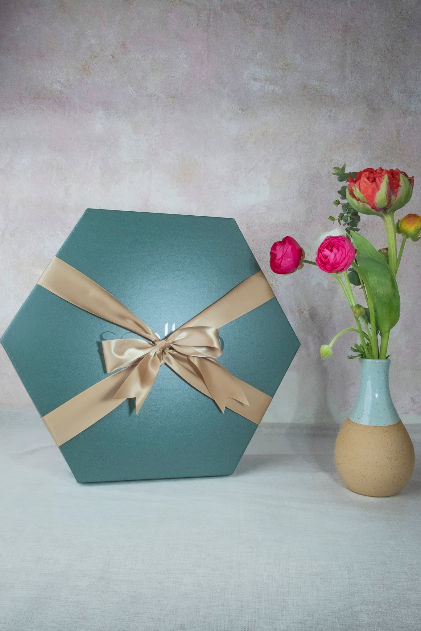 Scallop signature hexagon shaped emerald green gift boxes with satin gold ribbon bow